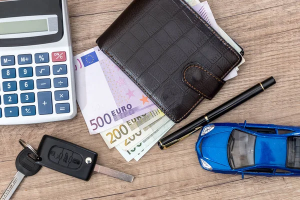 car key, toy car, euro bills on desk.