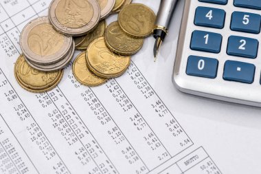 İş ve hesap makinesi, sikke, kalem ile finansal raporlar.