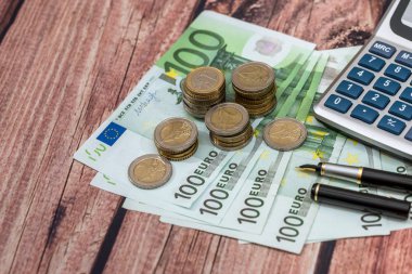100 Euro faturaları tükenmez kalem, sikke ve hesap makinesi.