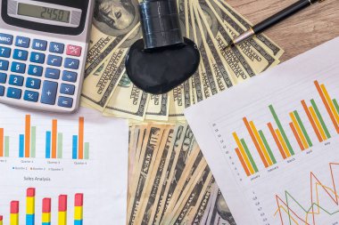 Masa üzerine dökülen petrol ile dolarlık banknot. hesap makinesi ile petrol üretim çizelgesi. iş kavramı.