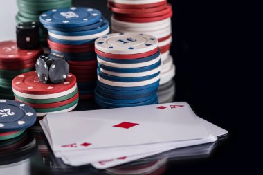 Poker fişleri ve siyahta izole oyun kartı