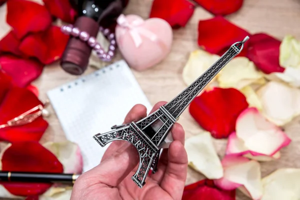 Eiffel tower model in hand on a background of petals of roses