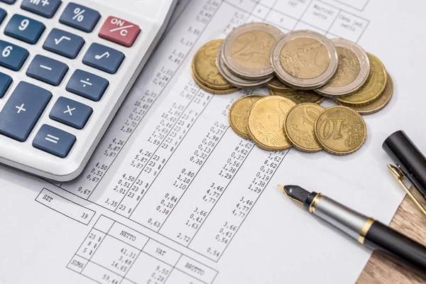 Business and financial reports with calculator, coin, pen.