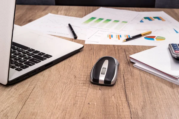 business workplace with laptop, graph, pen and calculator