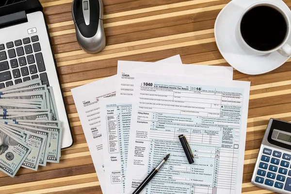 tax form with coffee, laptop, pen and calculator and dollar