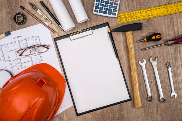 blank paper, house plan, helmet and work tolls on desk