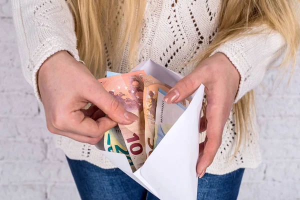 woman looks in the envelope - checks the salary