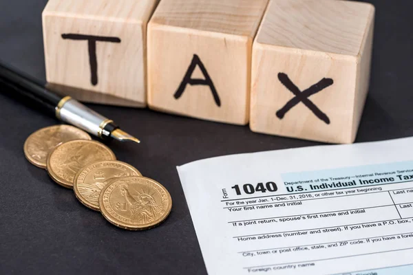 1040税形式 木立方体税钢笔和硬币在黑色 — 图库照片