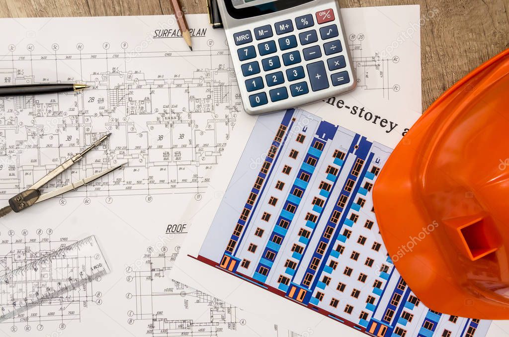hard hat with blueprints and rulers, pen, calculator on desk