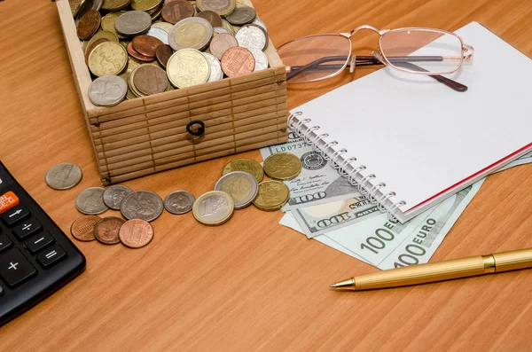 Hazine sandığı madeni para ile açın. Bize dolar ve euro boş not defteri, gözlük ve hesap makinesi