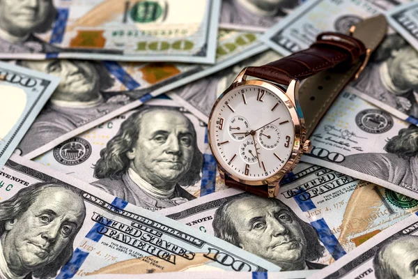 the concept of money with a hand-held clock and dollar bills