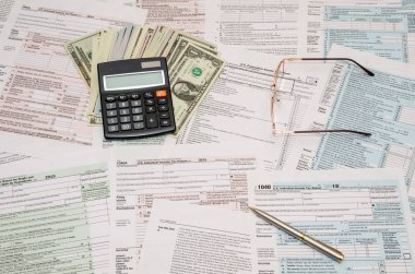 hesap makinesi, kalem ve dolar faturaları ile 1040 vergi formu