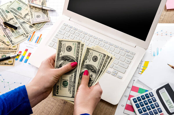 money in the hands of a laptop and graphics