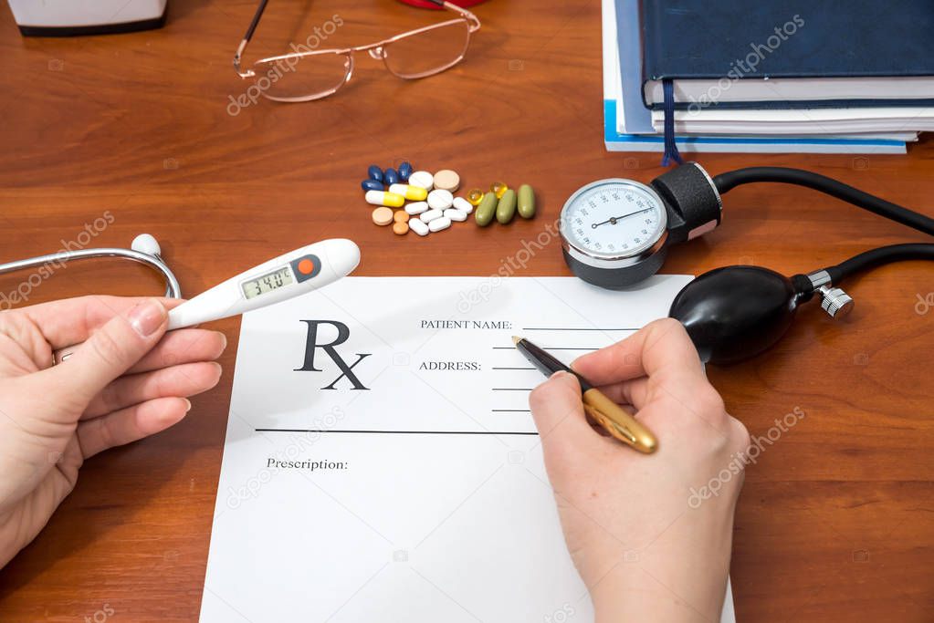 Doctor writing prescription with pills and stethoscope
