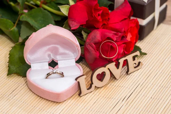 Wedding concept. text love with wedding rings, gift box and red roses