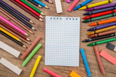 Okul malzemeleri - ahşap arka plan ve yer: Not defteri ve renkli kalemler metin için.
