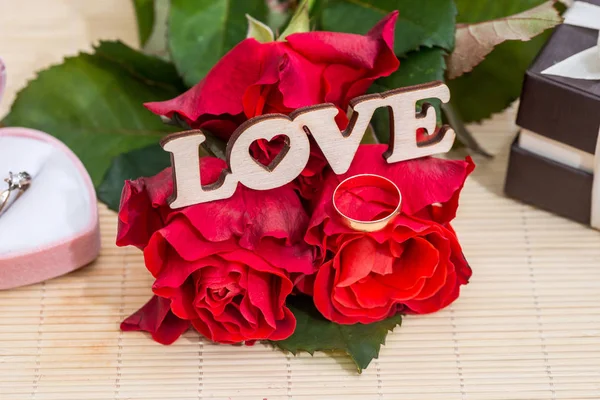 Wedding concept. text love with wedding rings, gift box and red roses