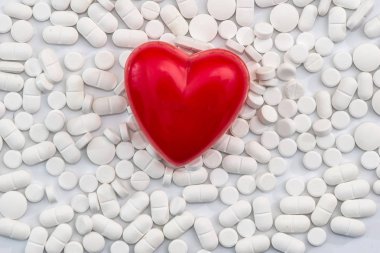 Dağınık beyaz tabletler üzerine, izole kırmızı kalpli