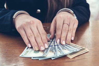 Elleri kelepçeli iş kadınının elleri dolar banknotlarıyla