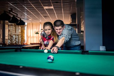 Genç ve güzel bir çift bilardo oynuyor.