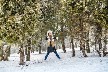 Ağaçların arasında genç bir bayanla kış parkı