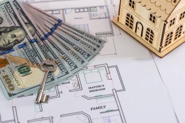 Planda dolar ve anahtar olan ahşap ev modeli.