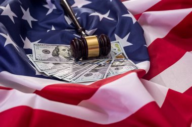 Amerikan bayrağında dolar banknotları olan yargıç tokmağı.