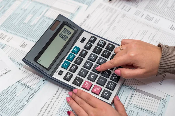 Manos femeninas con calculadora en forma de impuesto 1040 —  Fotos de Stock