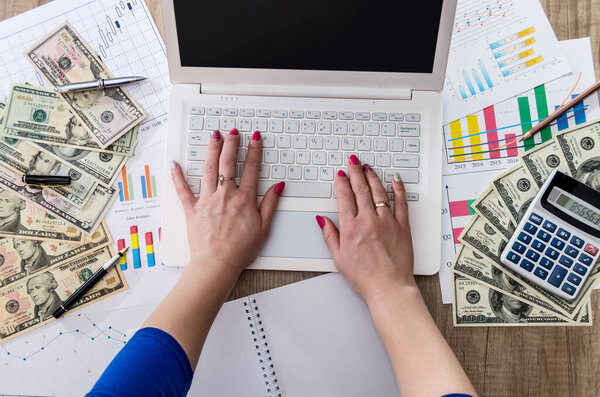 business worker is holding US dollars in hand with laptop and business graph