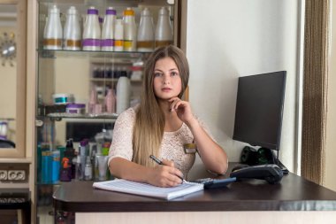 Güzellik salonunda resepsiyon masasının arkasında güzel bir genç kız.