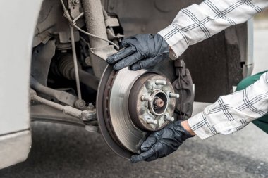 Brake disk with worker's hands in gloves close up