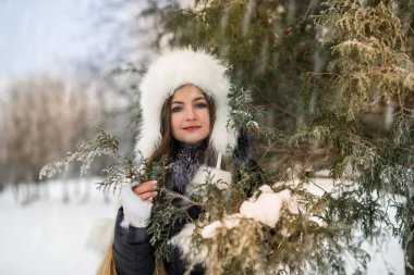Smiling beautiful woman with tree branches in winter park