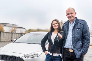 Happy and smiling couple posing near new car