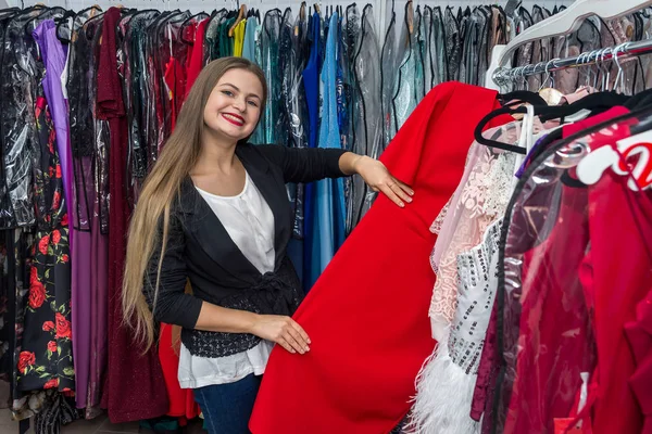 Smiling woman looking for dress in garment store