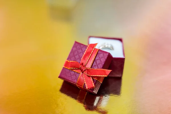 Anello dorato in scatola regalo rossa su sfondo dorato — Foto Stock