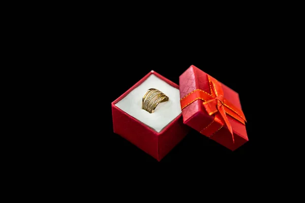 Red gift box with golden ring on black background — Stock Photo, Image