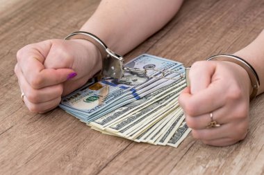 Dolar banknotlarında elleri kelepçeli bir kadın.