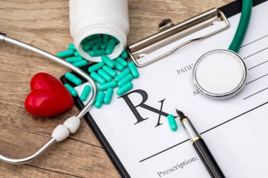Steteskop, kalem, oyuncak kalp ve haplı eczane tarifi içeren bir tablet.