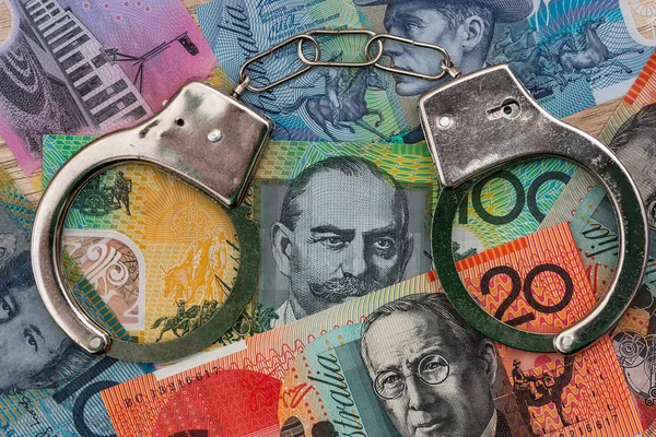Australian dollar banknotes with handcuffs on wooden table