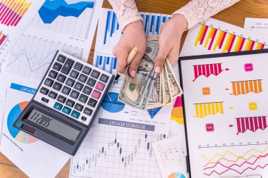 Dolar ve iş grafikleriyle kadın ellerinin üst görünümü