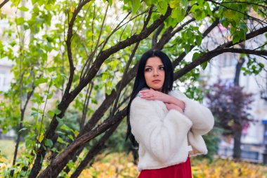 Güzel esmer, elleri göğsünde poz veriyor.