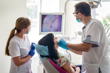Doktor, hastanın dişlerini intraoral kamerayla muayene ediyor.