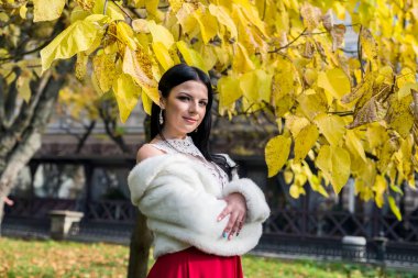 Güzel esmer, elleri göğsünde poz veriyor.