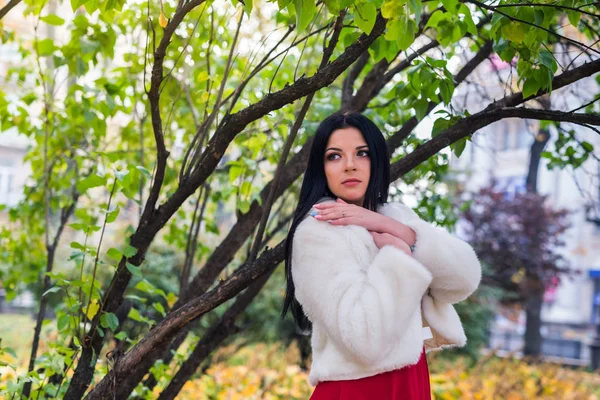 Güzel esmer, elleri göğsünde poz veriyor.