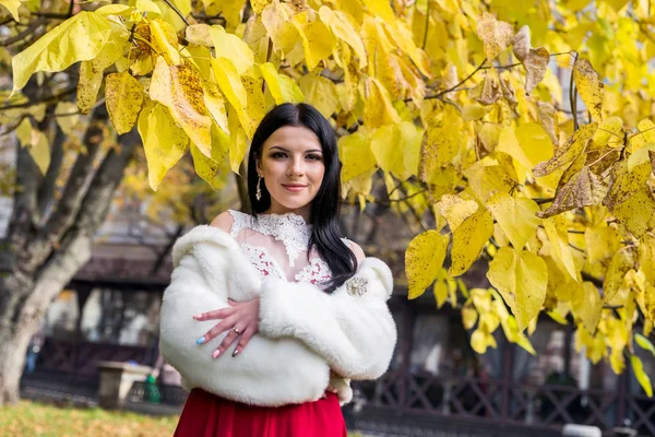 Güzel esmer, elleri göğsünde poz veriyor.