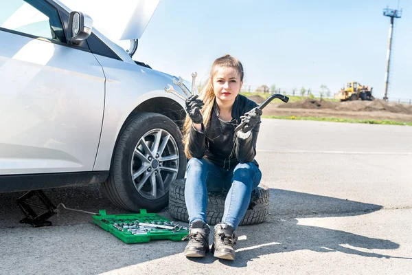 Woman with wrenches have a problem with car