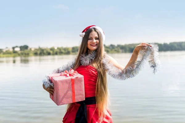 Hermosa mujer en vestido rojo con caja de regalo y guirnalda de Navidad — Foto de Stock