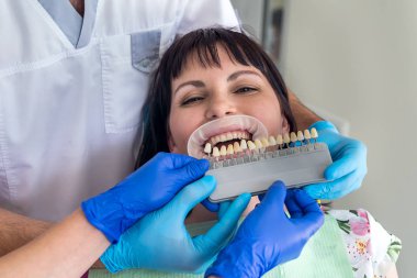 Doktor ve asistanı hastanın dişlerini örnekle karşılaştırıyor.