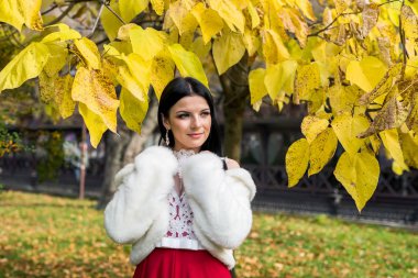 Güzel esmer, elleri göğsünde poz veriyor.