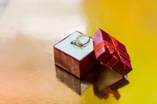 Obrączki ślubne w czerwonym pudełku na złotym tle — Zdjęcie stockowe